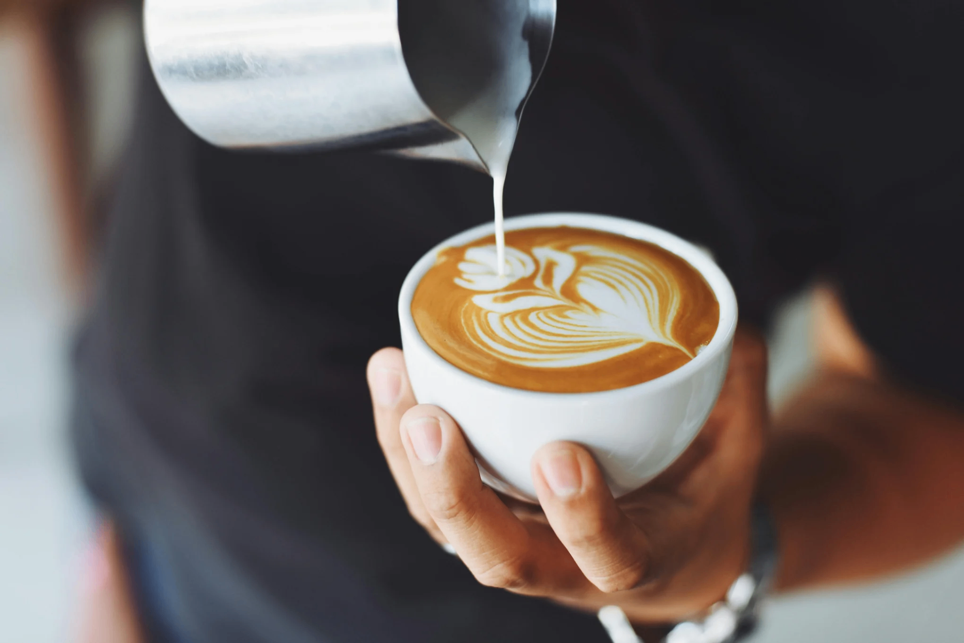 Barista pouring latte art at Brew District